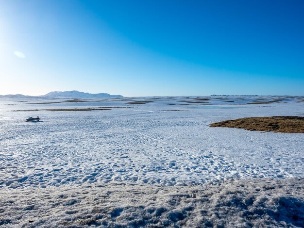 Schneefeld mit Bergen unter strahlend blauem Himmel im ländlichen Gebiet Islands