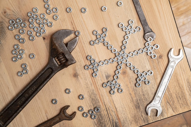 Foto schneeflocke aus metallmuttern und schraubenschlüsseln auf einem holztisch wintersymbol neujahr und