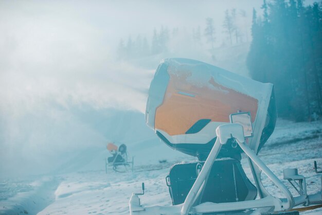 Schneekanone in den Winterbergen. Schneekanone, die künstliche Eiskristalle sprüht. Maschinen, die Schnee machen.