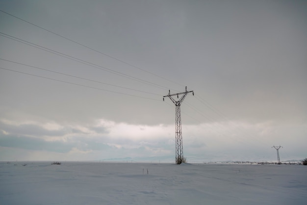 Schneelandschaft des Winters mit elektrischen Säulen im Feld