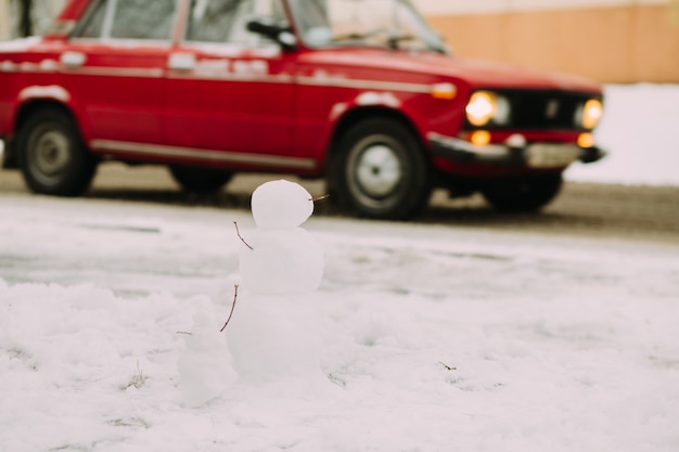 Schneemänner an der straße mit rotem auto