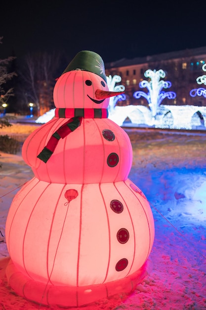 Schneemänner beleuchtet mit bunten Lichtern in der nächtlichen Neujahrsstadt