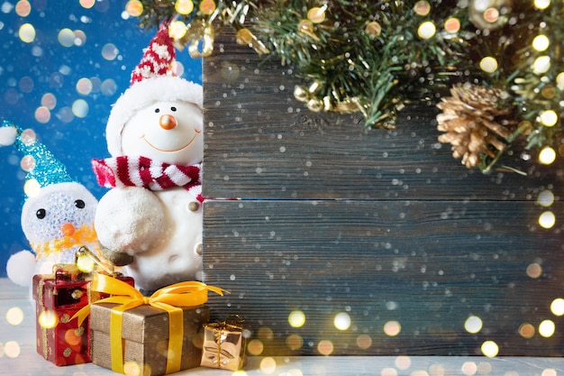 Schneemann mit Geschenken und Weihnachtsbäumen und wartet auf den Weihnachtsmann. Die Konzeptpostkarte von Weihnachten und dem neuen Jahr. Platz kopieren.