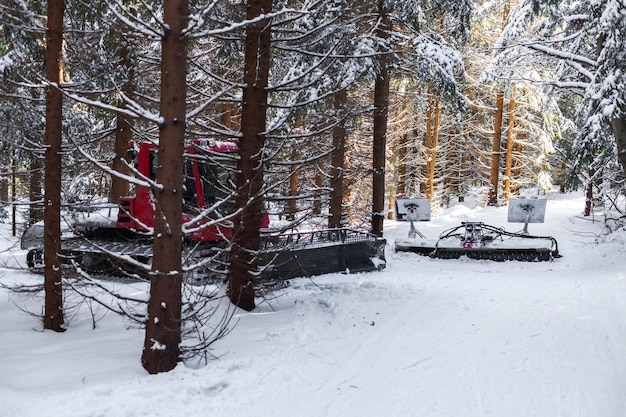 Schneemobil im verschneiten Wald macht eine Loipe für Langläufer