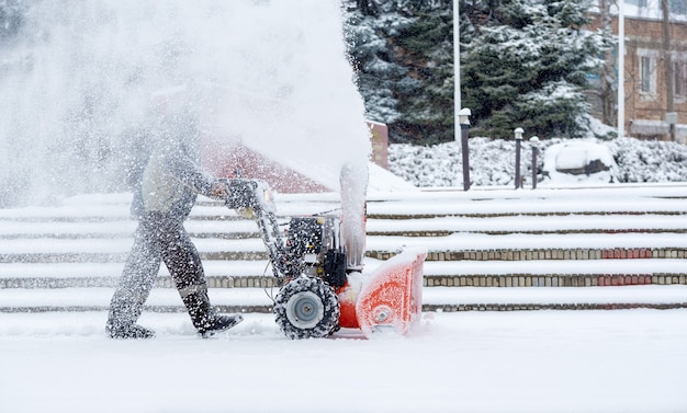 Schneeräumarbeiten mit einer Schneefräse. Mann, der Schnee entfernt. Starkniederschläge und Schneehaufen