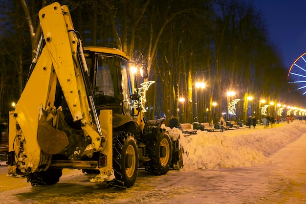 Schneeräumung im Park im Winter mit einem Traktor am Abend