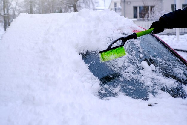 Schneereinigung aus dem Auto mit einem Pinsel in Nahaufnahme