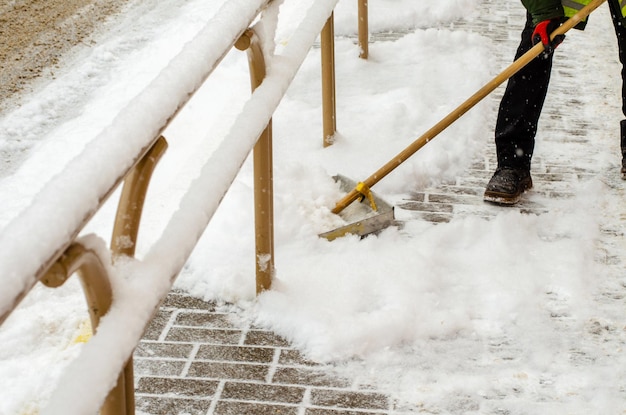 Schneesturm in der Stadt Straßen und Bürgersteige mit Schnee bedeckt Arbeiterschaufel räumt Schnee Schlechtes Winterwetter Straßenreinigung nach Schneesturm