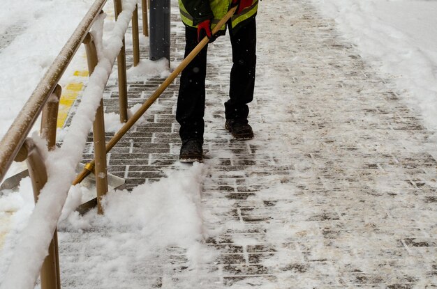 Schneesturm in der Stadt Straßen und Bürgersteige mit Schnee bedeckt Arbeiterschaufel räumt Schnee Schlechtes Winterwetter Straßenreinigung nach Schneesturm