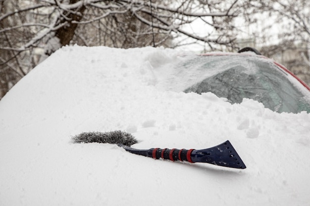 Foto schneewehe und bürste auf der windschutzscheibe des autos. auto vom schnee reinigen. konzept von schlechtem wetter, schneesturm