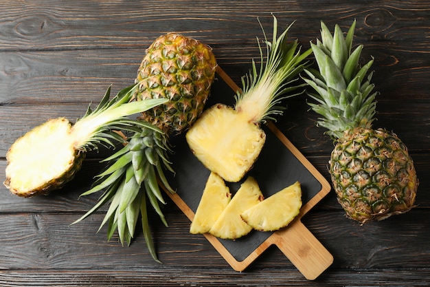 Schneidebrett mit Ananas auf hölzernem Hintergrund, Draufsicht