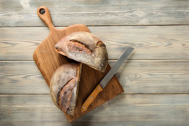 Schneidebrett mit einem geschnittenen Brotlaib. Hausgemachtes Brot halbiert auf einem Holztisch mit Kopierraum.