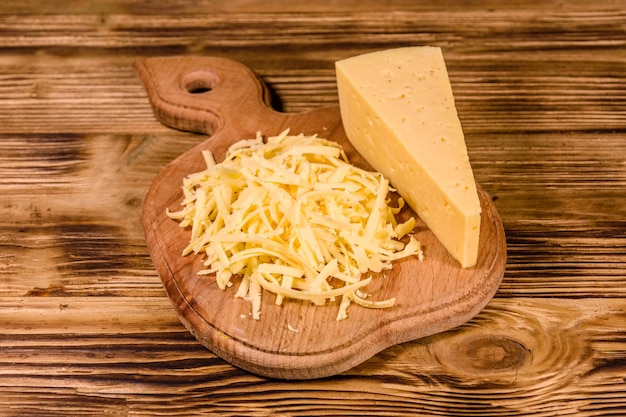 Schneidebrett mit geriebenem Käse auf rustikalem Holztisch