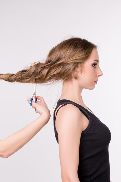 Schneiden der langen Haare des schönen Mädchens