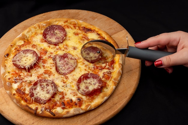 Schneiden Sie die Pizza mit Salami und Käse mit einem speziellen Messer