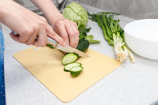 Schneiden Sie eine Gurke für Salat mit einer Messernahaufnahme
