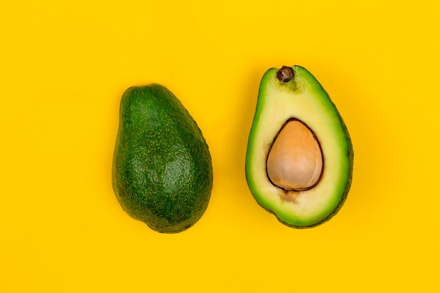 Schneiden Sie frische reife Avocado auf gelbem Hintergrund