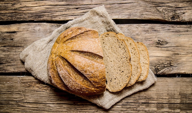 Schneiden Sie frisches Brot auf alten Stoff. Auf Holztisch.