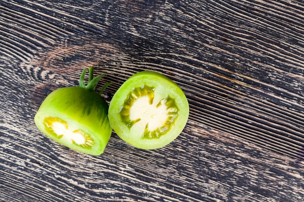 Schneiden Sie grüne Tomate auf einem schwarzen Tisch, Nahaufnahme eines Gemüses