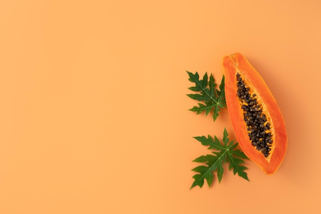 Foto schneiden sie papaya über orangefarbenen tischhintergrund für tropisches obst-design-konzept top-view-kopierraum