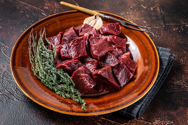 Schneiden Sie Rindfleisch oder Kalbfleisch rohes Herz in einen rustikalen Teller mit Kräutern. Draufsicht.