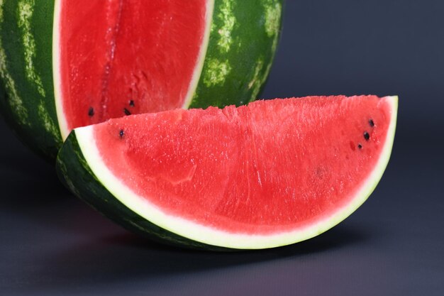 Schneiden Sie Stücke von roter, reifer, köstlicher, saftiger Wassermelone auf schwarzem Hintergrund