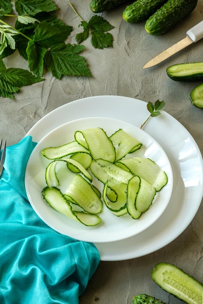 Schneiden von Gurken auf einer Gabel kreatives Foto von frischen Gurken auf einem konkreten Hintergrund