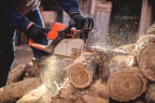 Schneiden von Holz mit Kettensäge im Hinterhof, Holzfällerberuf.