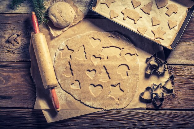 Schneiden von Lebkuchenplätzchen für Weihnachten auf alten Holztisch