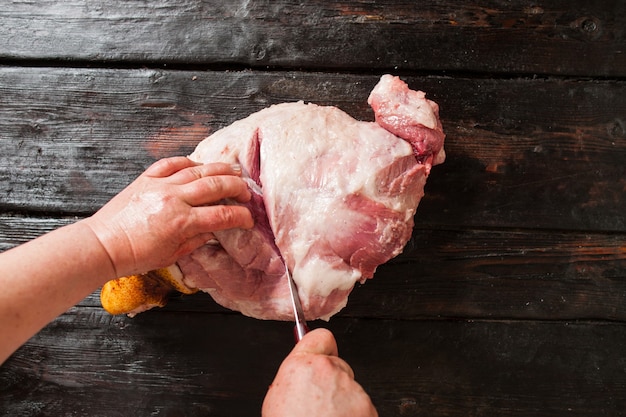 Schneiden von Schweinefleischstück auf Holztisch