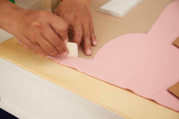 Schneider arbeitet mit Stoff am Tisch im Atelier von oben