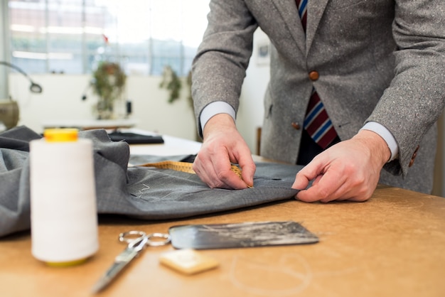 Schneider, der mit Jacke in der Werkstatt arbeitet