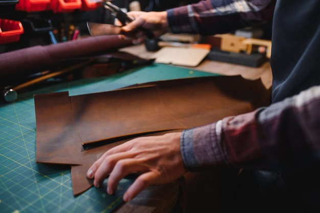 Schneider-Schuhmacher hält verschiedene Rollen aus natürlichem braunem Leder und arbeitet mit Textilien in der Werkstatt