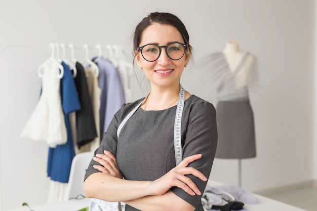 Schneiderin, Modedesignerin und Schneiderin - Junge Schneiderin Frau über Kleiderständer mit