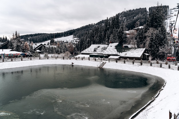 Schneiende Winterlandschaft mit dem zugefrorenen See in den Bergen. Vereiste Wasseroberfläche. Konzept der Wintersaison