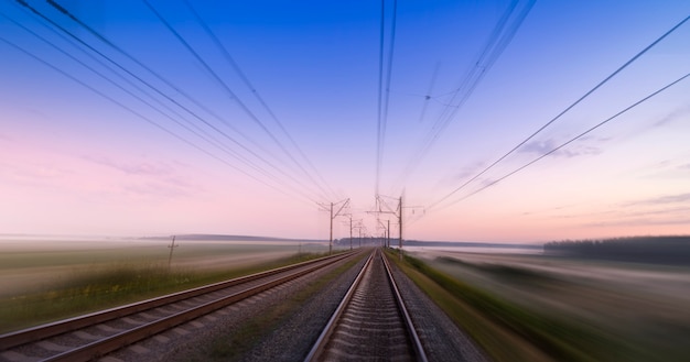 Foto schnelle bewegung über die bahnlinie. konzept, bahnlieferung, reise und geschwindigkeit. leere eisenbahn im morgengrauen oder sonnenuntergang.