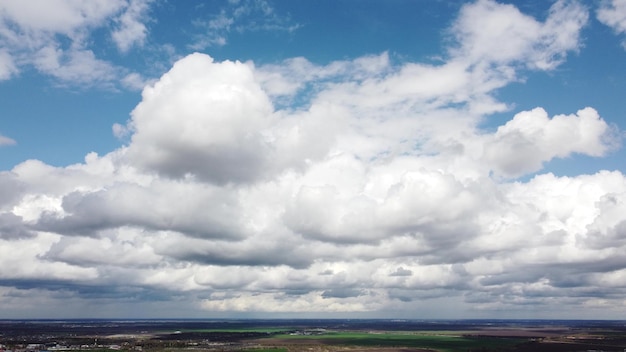 Schnelle Bewegung weißer Cumulus-Wolken am blauen Himmel bei starkem Wind während der Tageszeitraffer-Luftfahrt