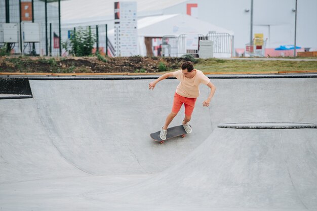 Schneller Skater in bunten Kleidern, der auf ihrem Board auf dem Quarterpipe-Kreis im Skatepark reitet. Langer Schuss.