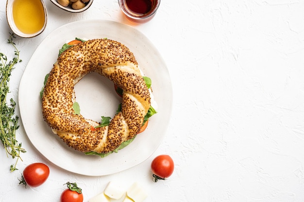 Schnelles türkisches Frühstück Simit mit Käse und Gemüse mit Glas türkischem Schwarztee mit Glas türkischem Schwarztee auf weißem Steintisch Hintergrund Draufsicht flach lag mit Kopierraum für Text