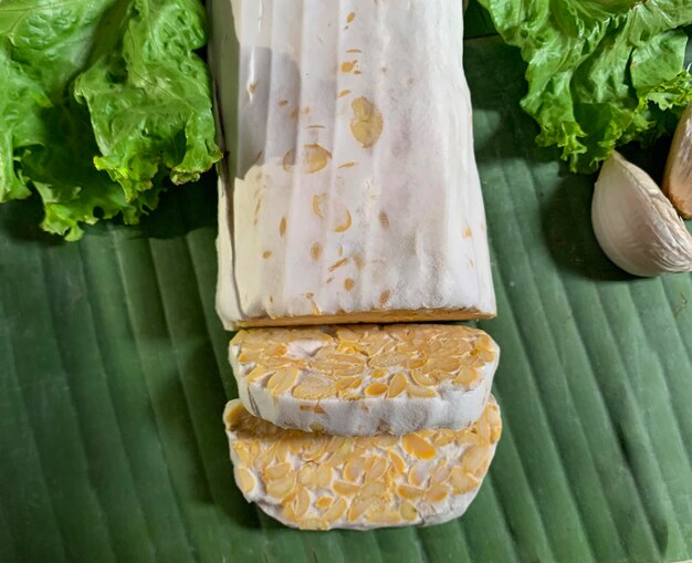 Foto schnitte tempe oder tempeh auf bananenblättern mit gemüse indonesisches traditionelles essen aus fe