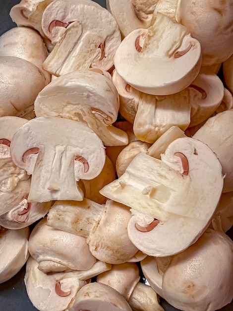 Foto schnittgeschnittene champignon-pilze auf schwarzem hintergrund nahaufnahme