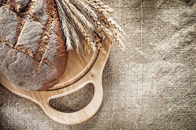 Schnitzbrett Brot Bündel Weizenähren auf Sackleinen Hintergrund