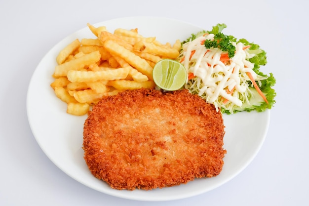 Schnitzel de cerdo con papas fritas y verduras en plato blanco