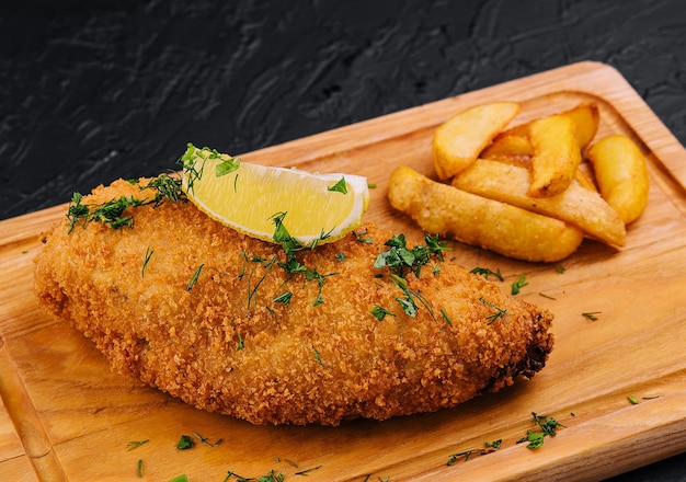 Schnitzel empanado con papas fritas en una tabla para cortar