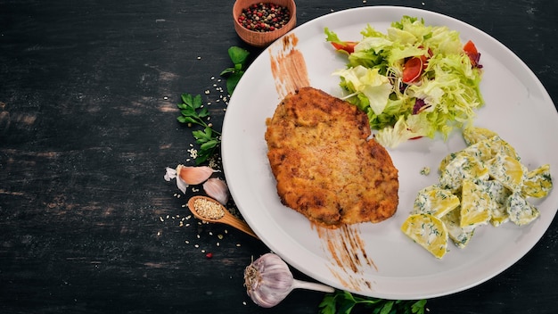 Schnitzel frito con patatas y verduras Vista superior Sobre un fondo de madera Espacio de copia