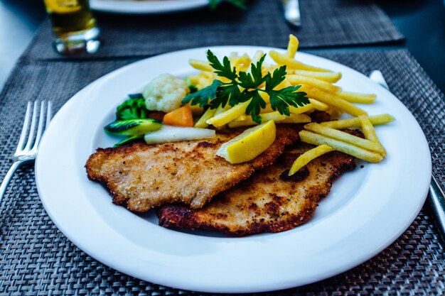 Foto schnitzel mit pommes serviert auf dem teller auf dem tisch