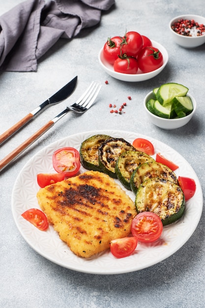 Schnitzel von Huhn und Zucchini auf dem Grill gekocht. Frische Tomaten auf einem Teller. Fertig leckeres Mittagessen.