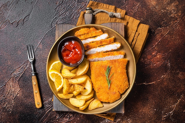 Schnitzel weiner alemán empanizado con gajos de patata Fondo oscuro Vista superior