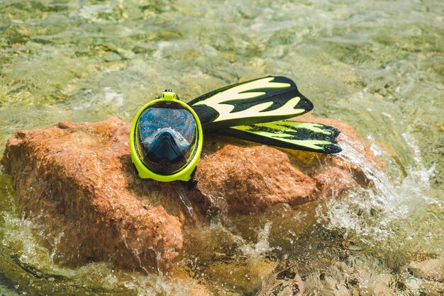 Schnorchelmaske mit Flossen am Felsen im Meerwasserkopierraum