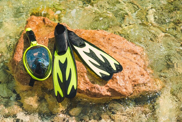 Schnorchelmaske mit Flossen am Felsen im Meerwasserkopierraum